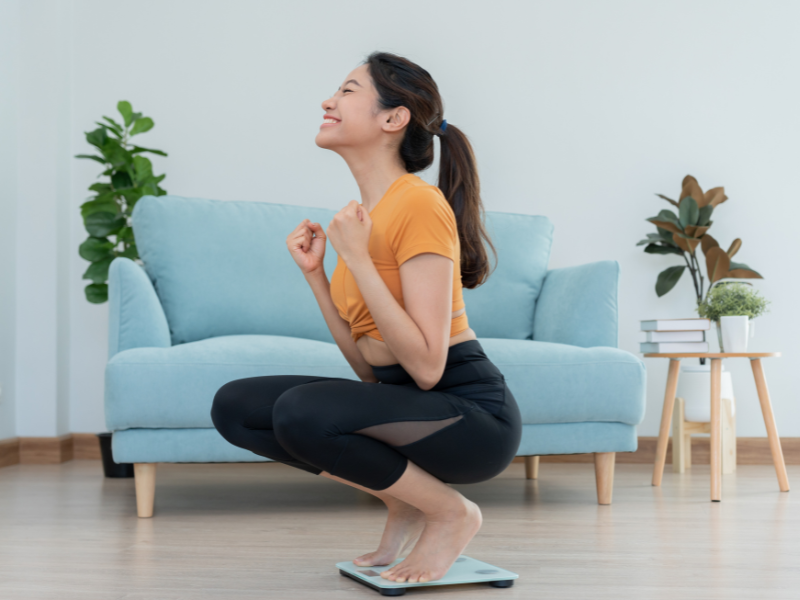 Frau steht glücklich auf der Waage